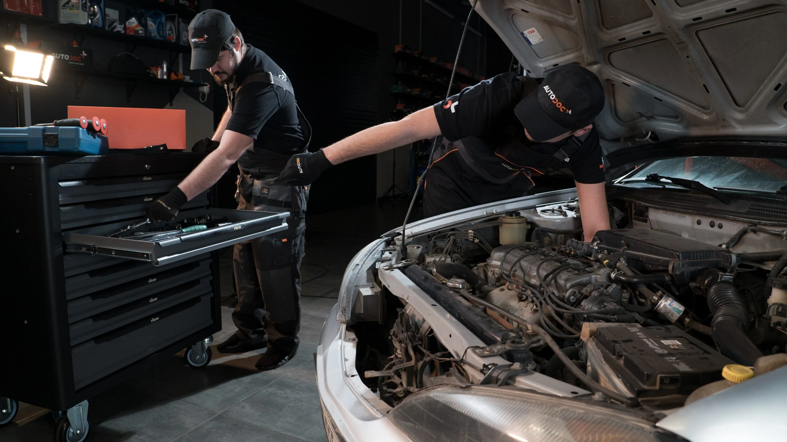 Zwei AUTODOC-Mechaniker reparieren ein Auto.