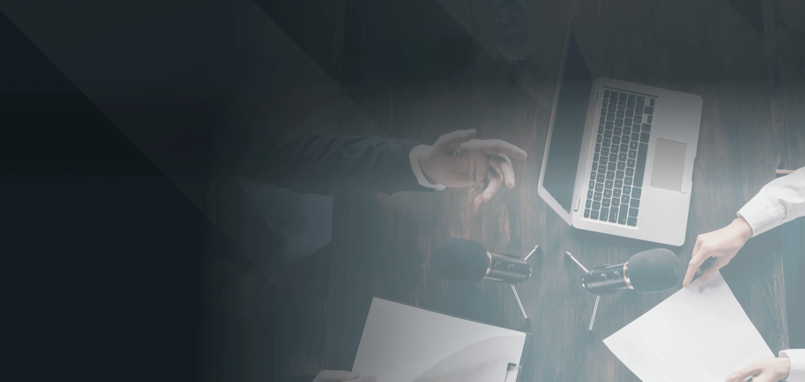 a person sitting at a desk with a microphone and a laptop