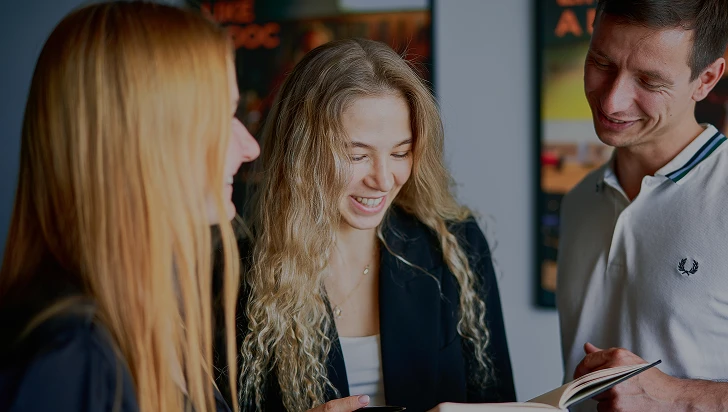 a group of women smiling and looking at a book