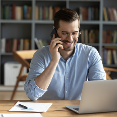 a man talking on a cell phone while looking at a laptop